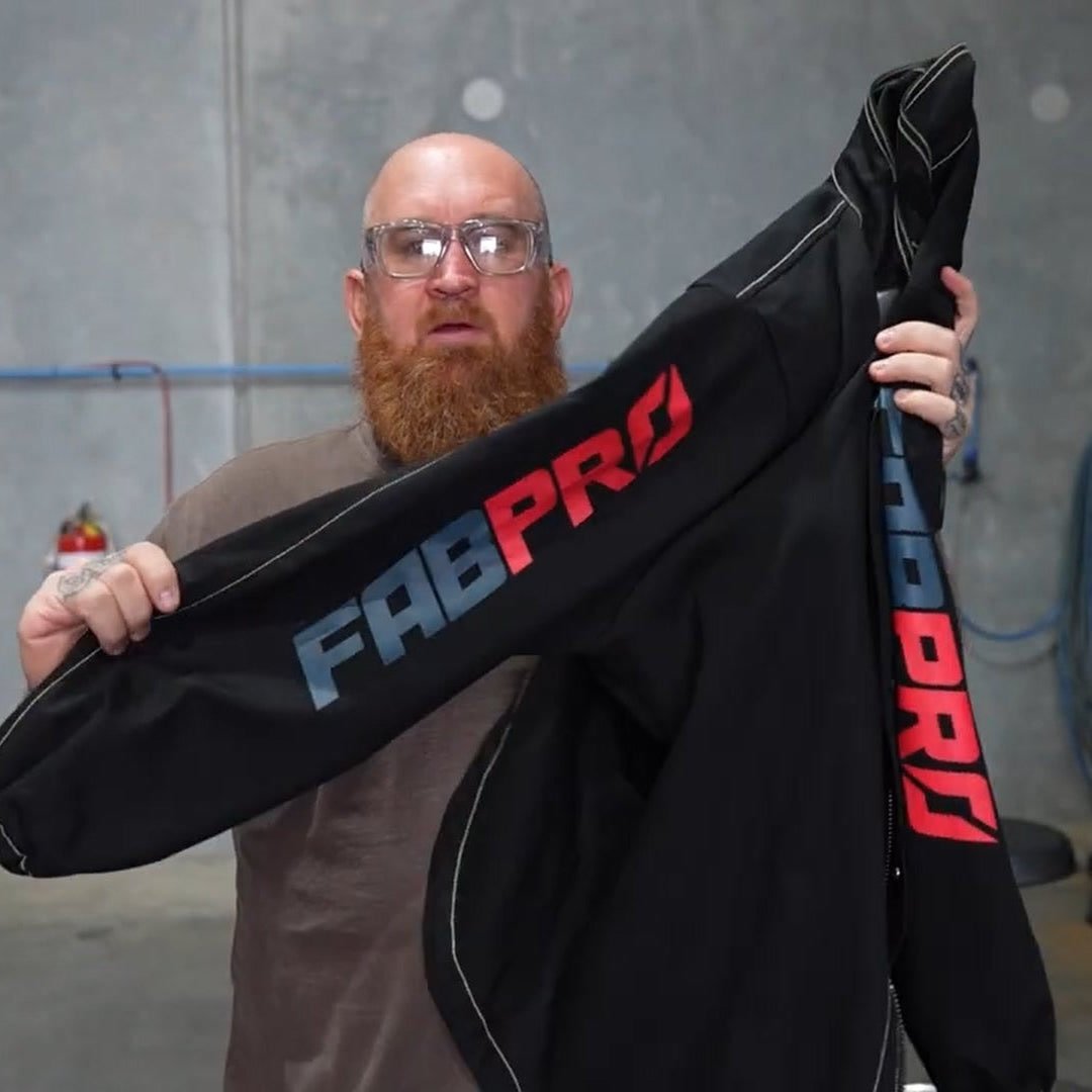The FabPro founder in the workshop holding a black FabPro welding jacket